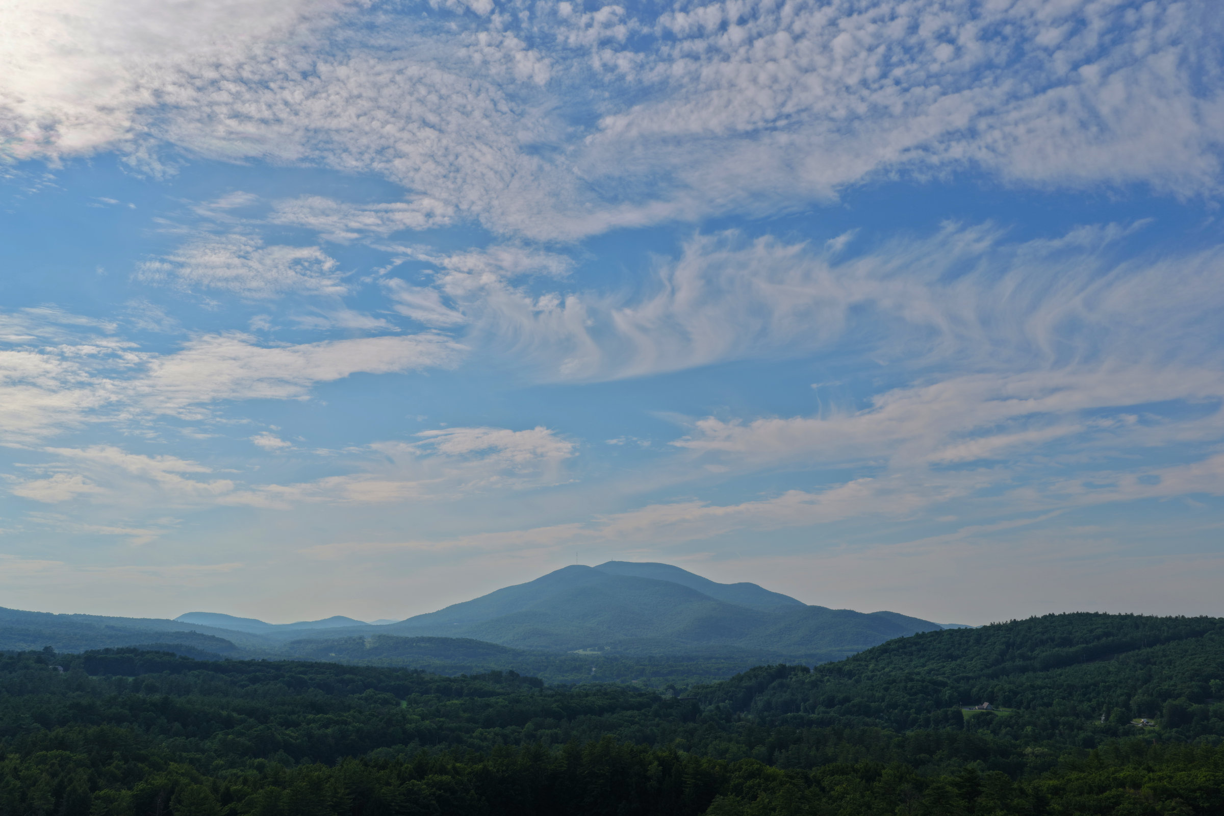 Mount Ascutney rising above forested hills under a wide cirrus sky