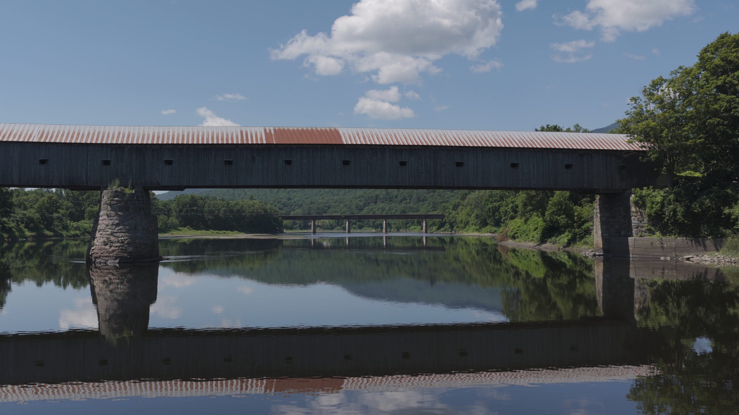 The covered bridge at water level with its reflection in still river