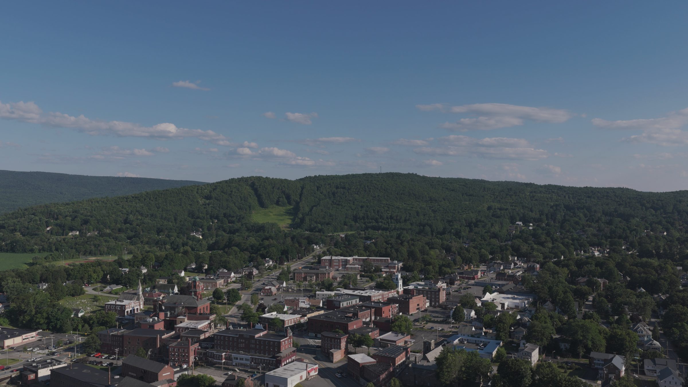 Claremont rooftops below a long forested ridge