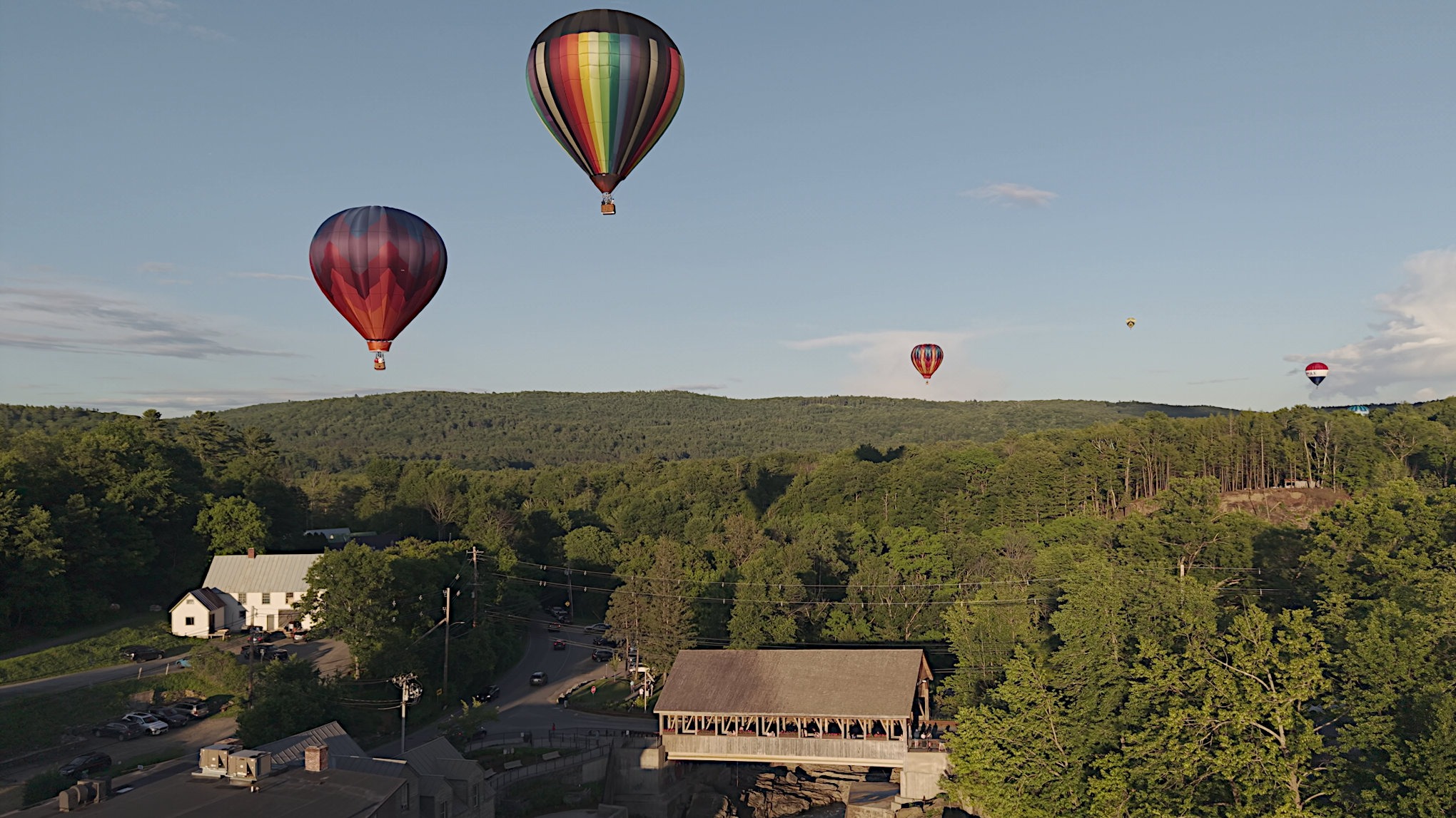 Hot air balloons drifting above the Quechee covered bridge at golden hour