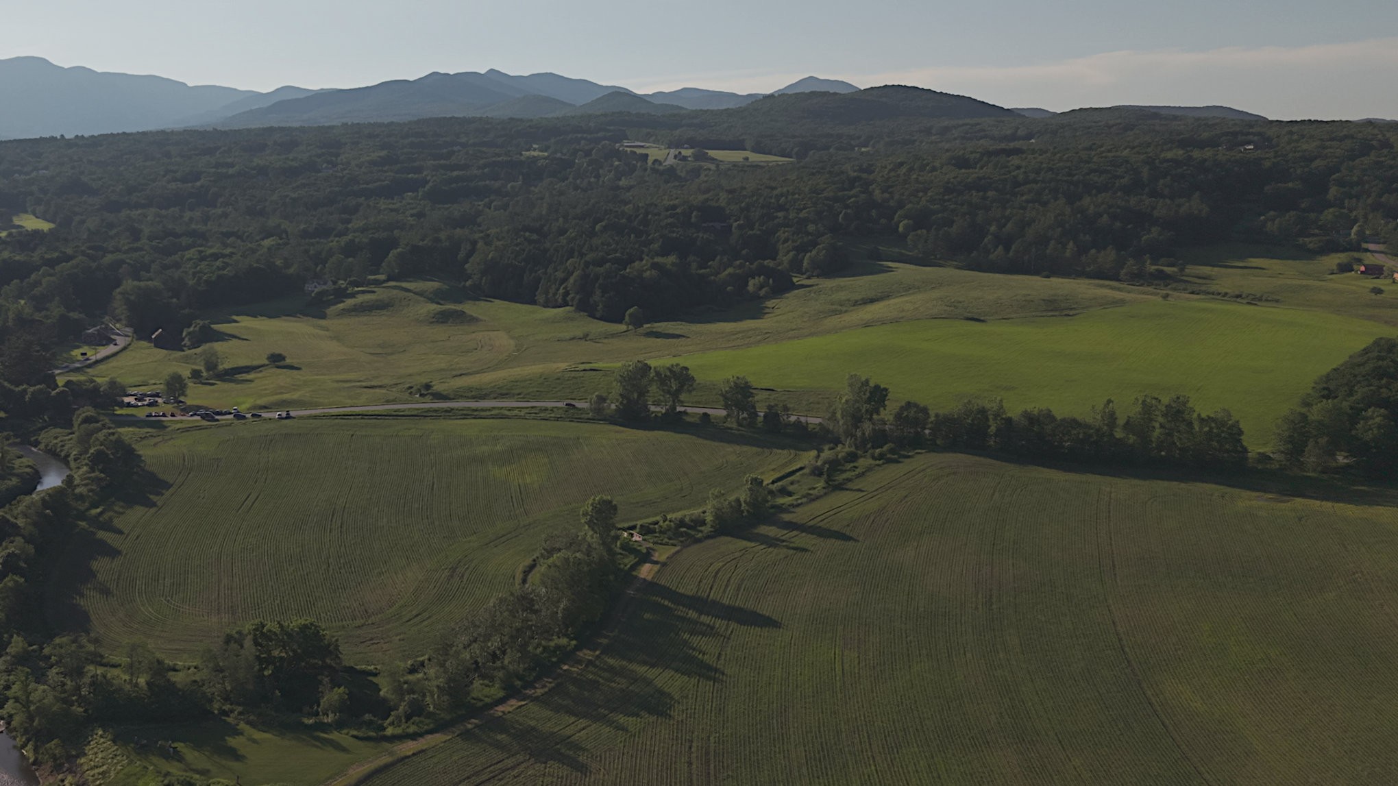 Green Mountain ridgeline above mown hayfields and a river bend